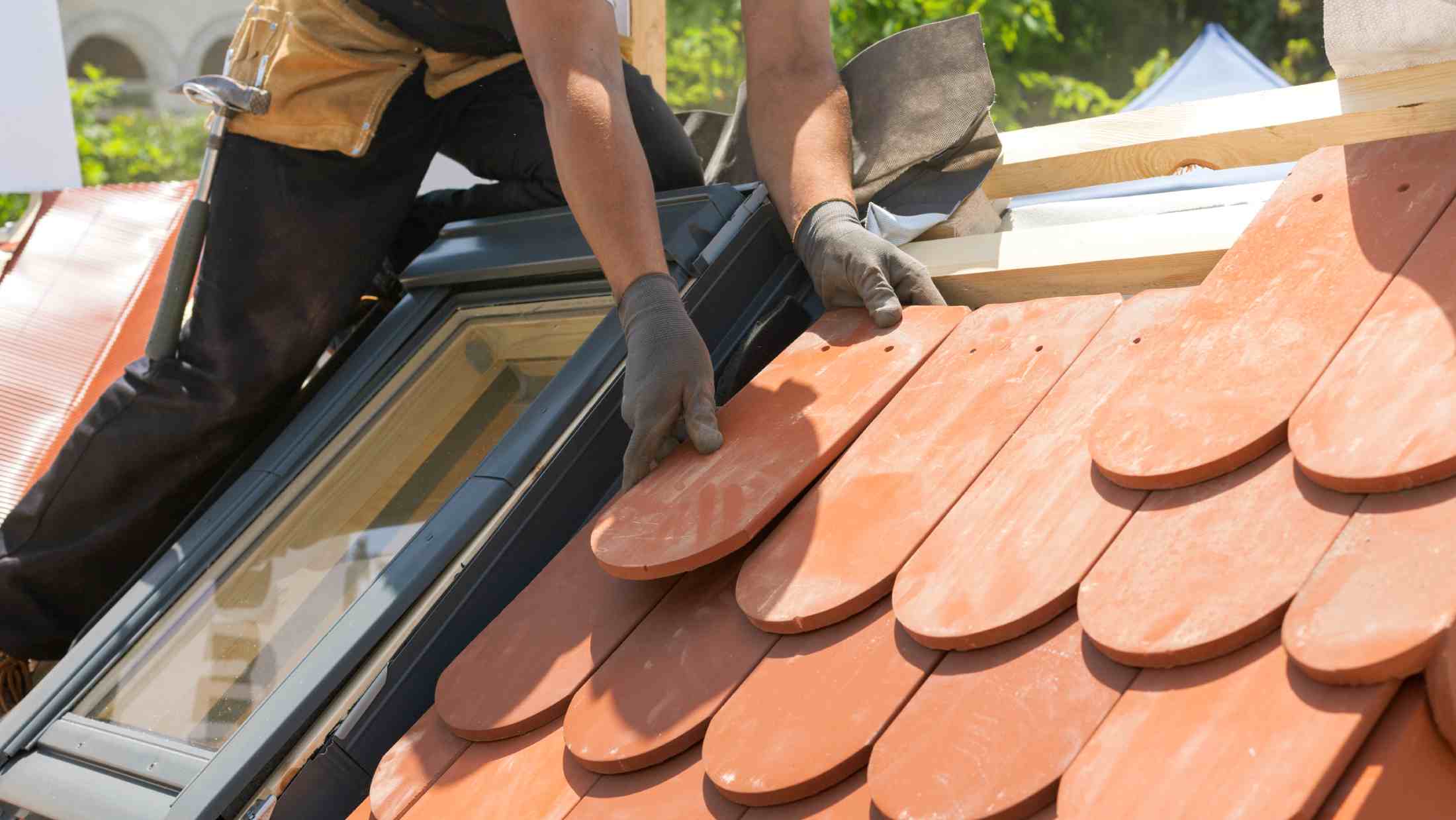 Hands of roofer laying tile on the roof