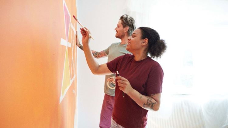 happy couple painting on wall in their new home
