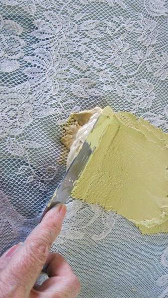 Yelow paint being applied over a sheet of lace