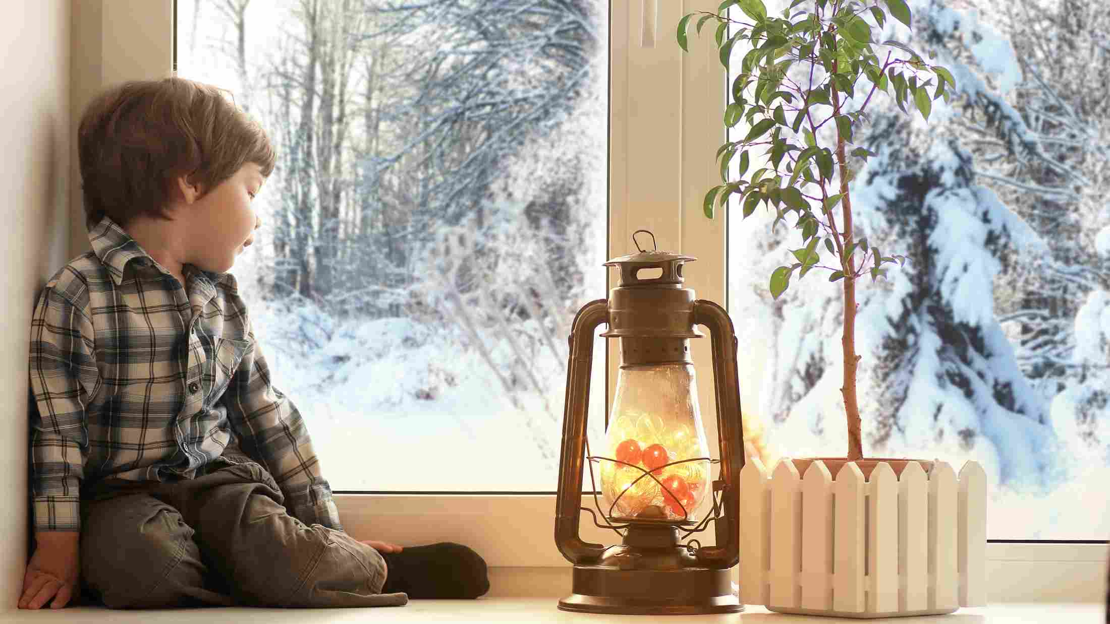 Little boy sitting by a white window