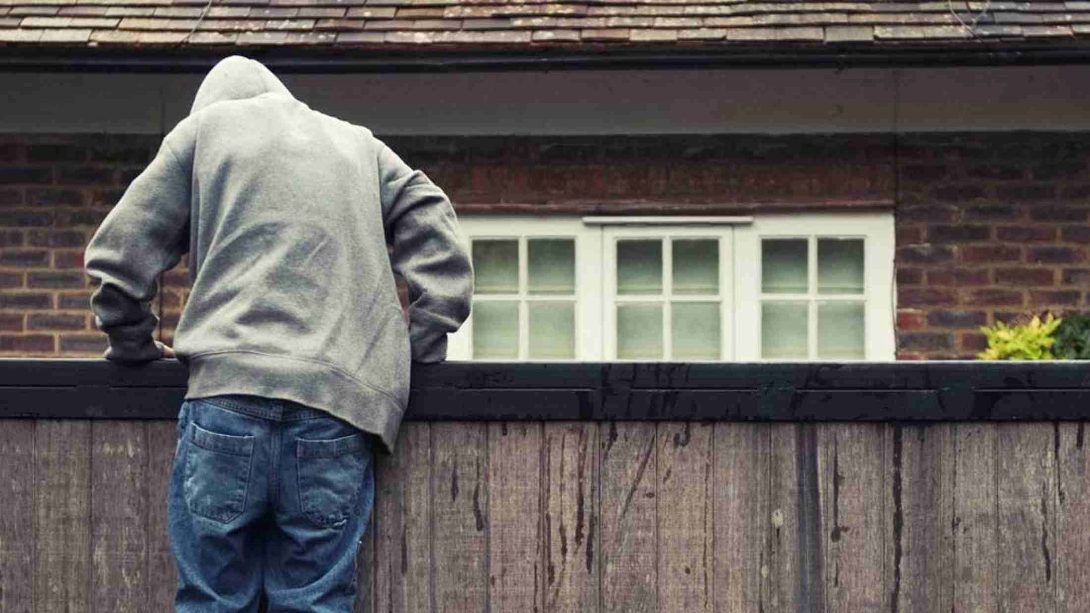 A thief climbing over a wooden fence