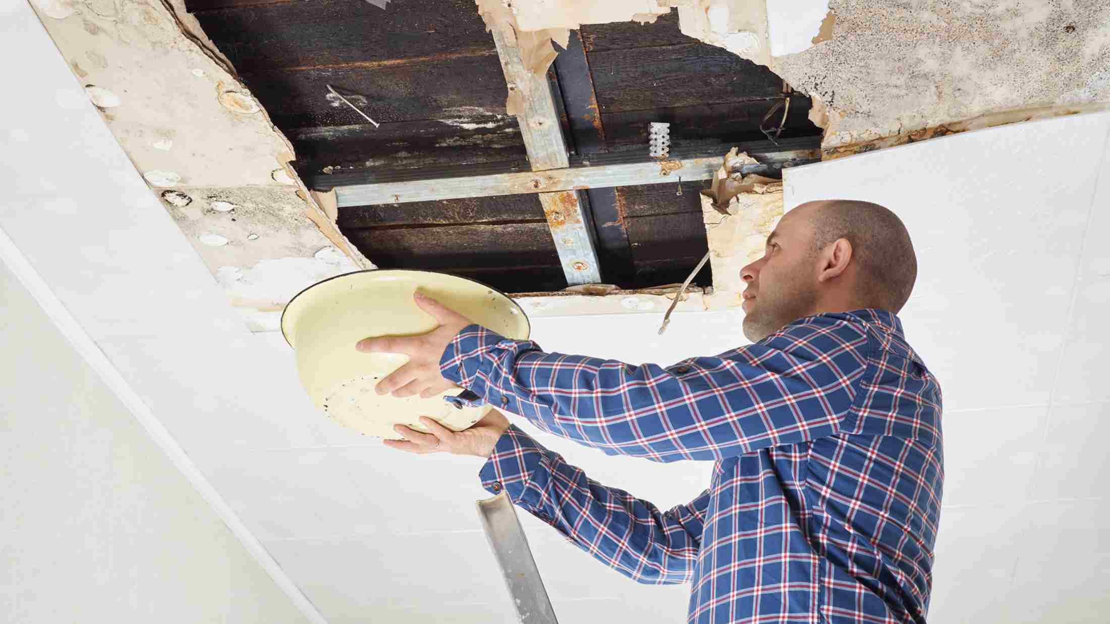 Man holding bucket up to ceiling