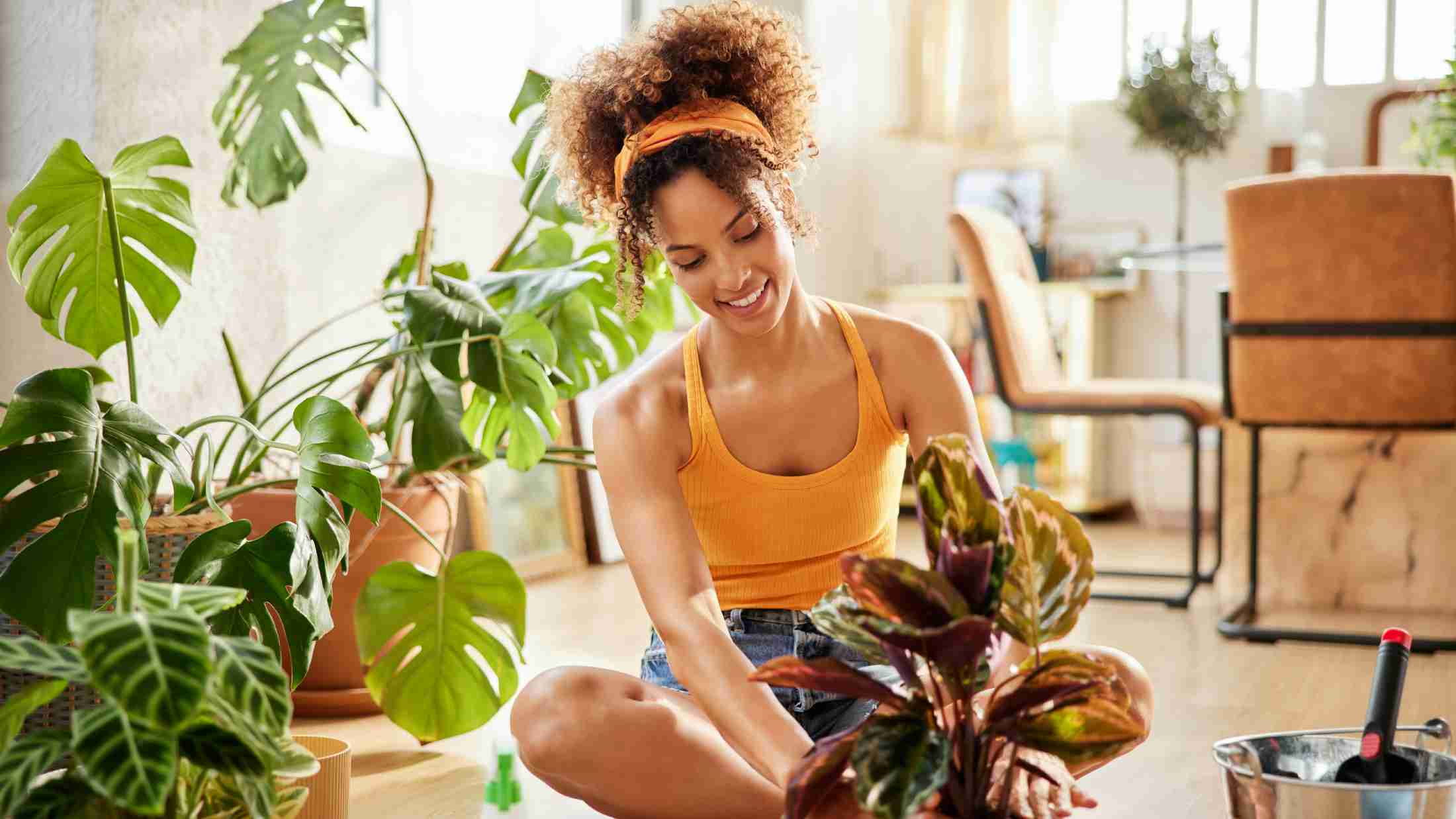 Smiling woman planting while slitting cross legged by potted plants