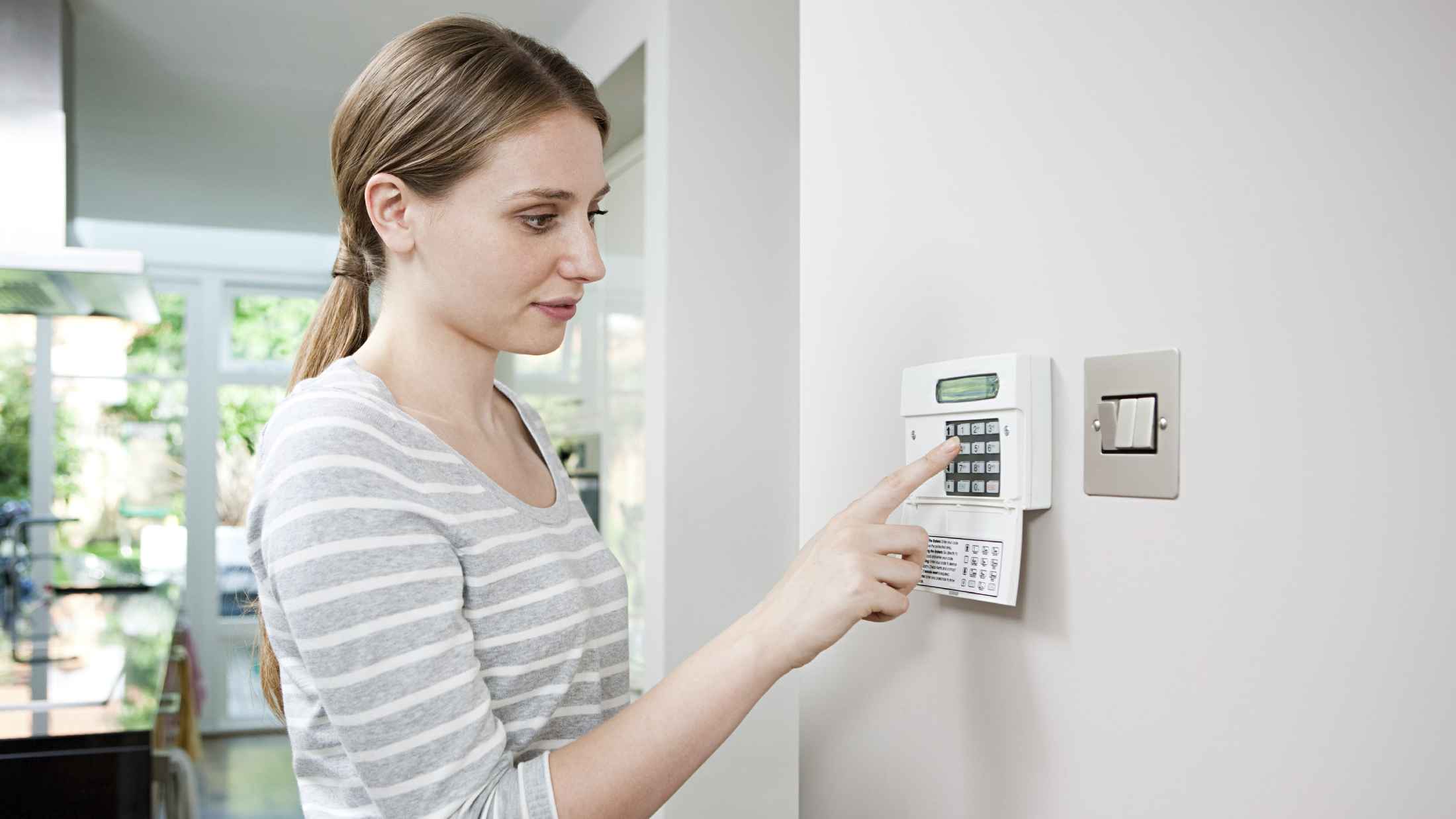 Woman setting burglar alarm via control panel.jpg