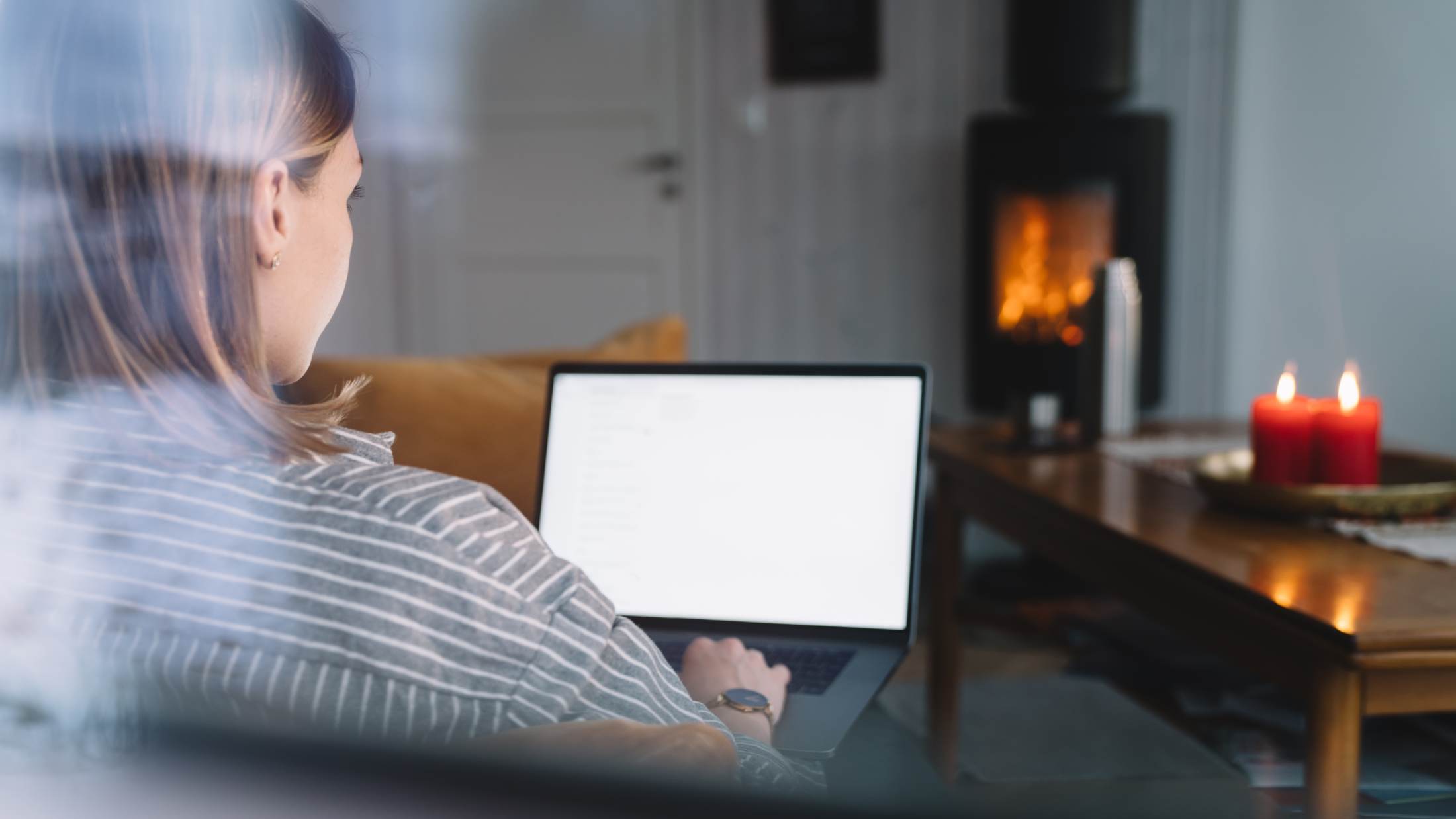 Woman working on laptop in front of open fire