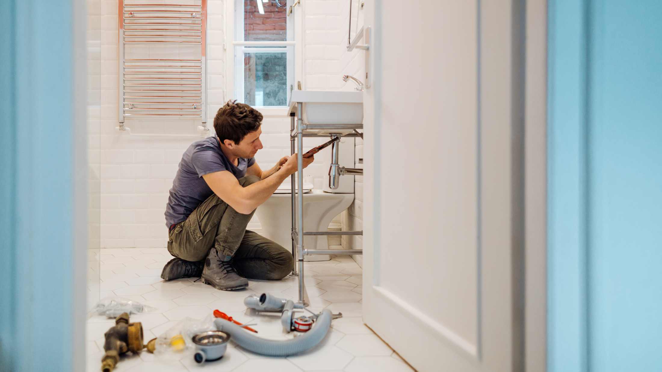 Young man fixing a leak under the bathroom sink