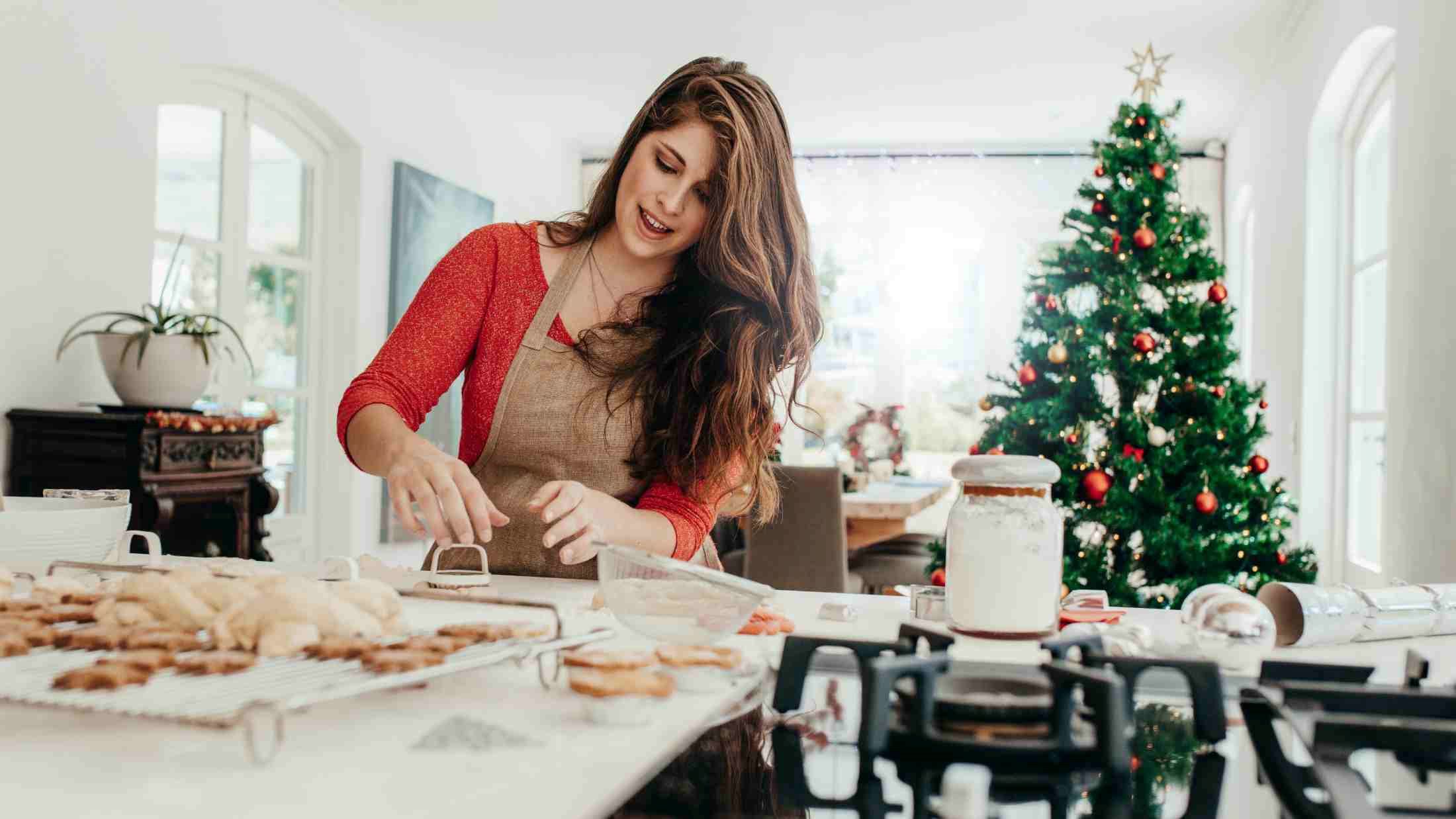 Young woman making shaped cookies with cutter for Christmas