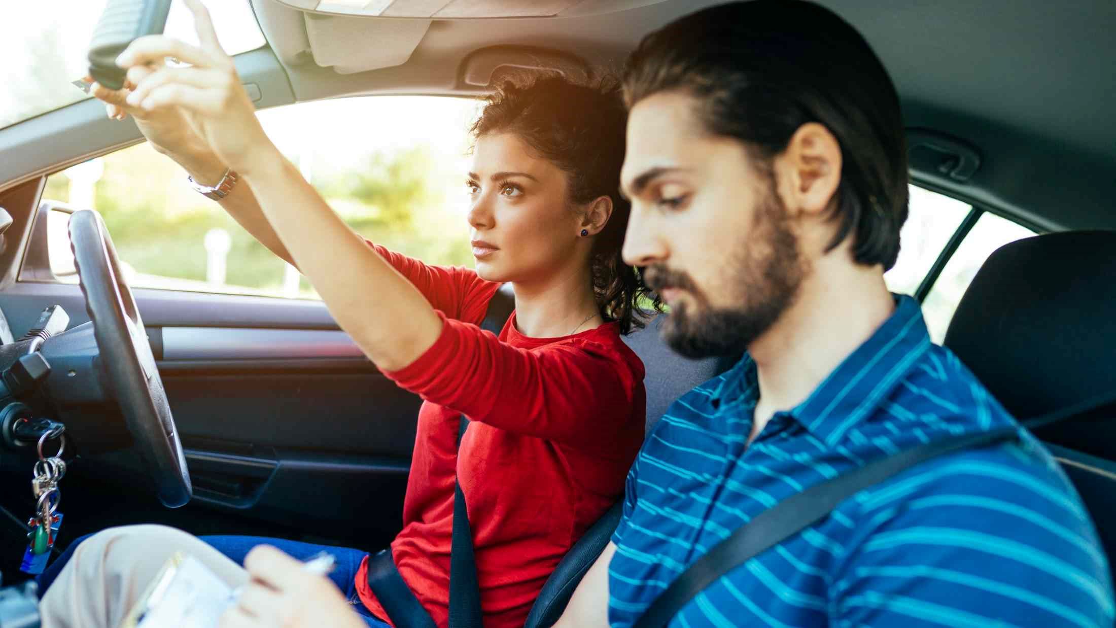 A female adjusting the rear mirror before her driving exam