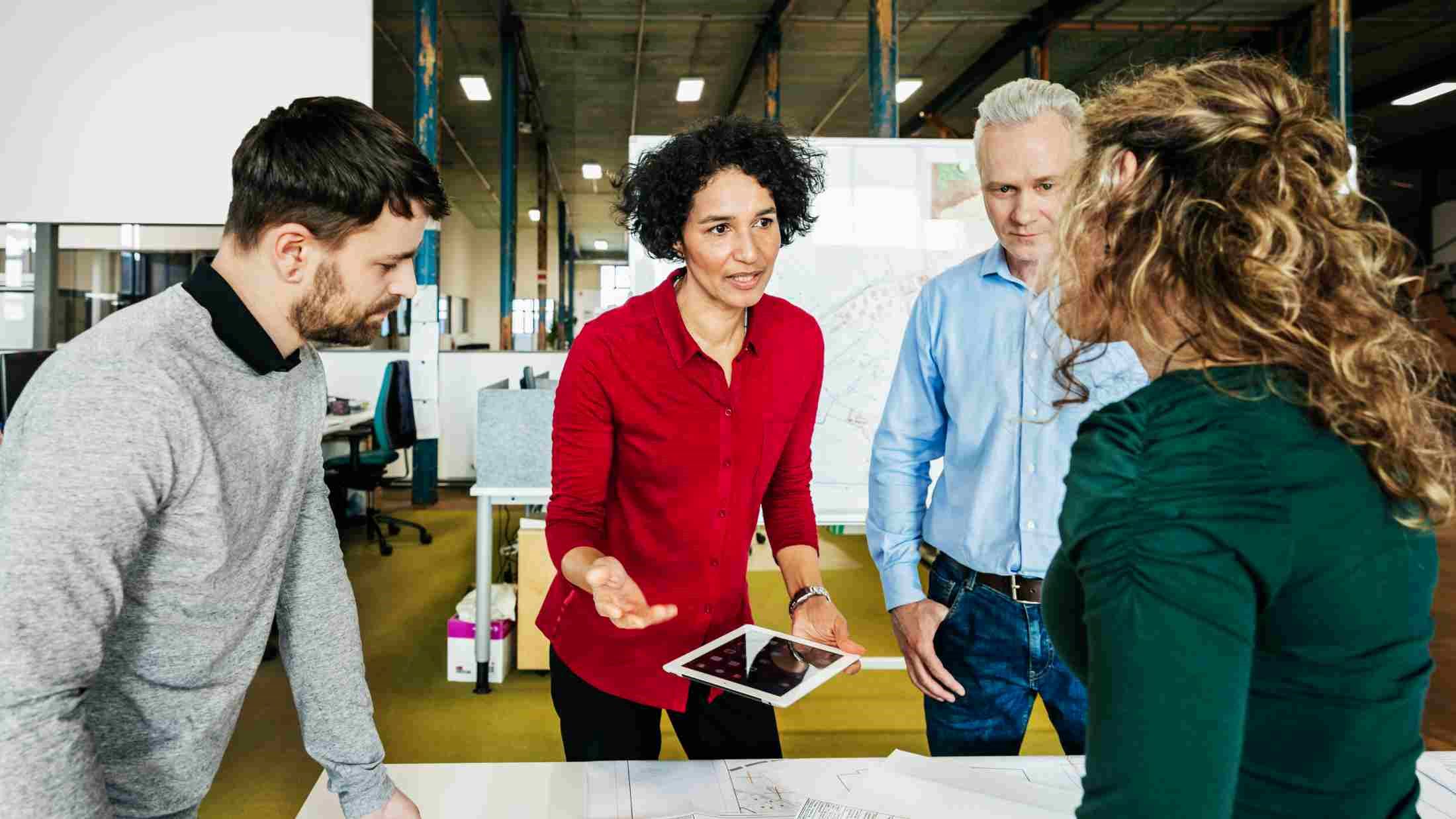 A group of business colleagues standing, having a meeting together in an office