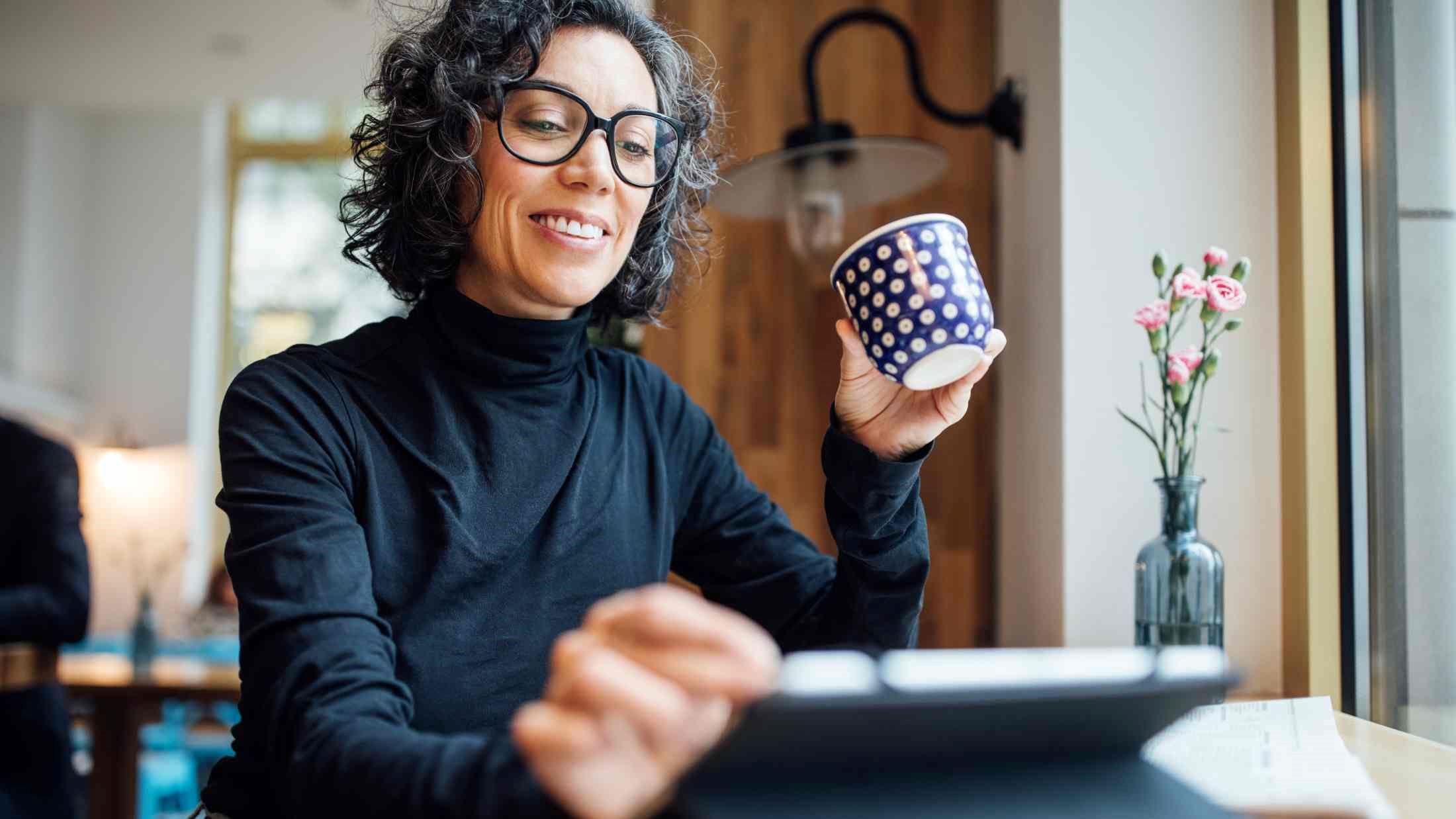 A woman on a tablet with a cup in her hand