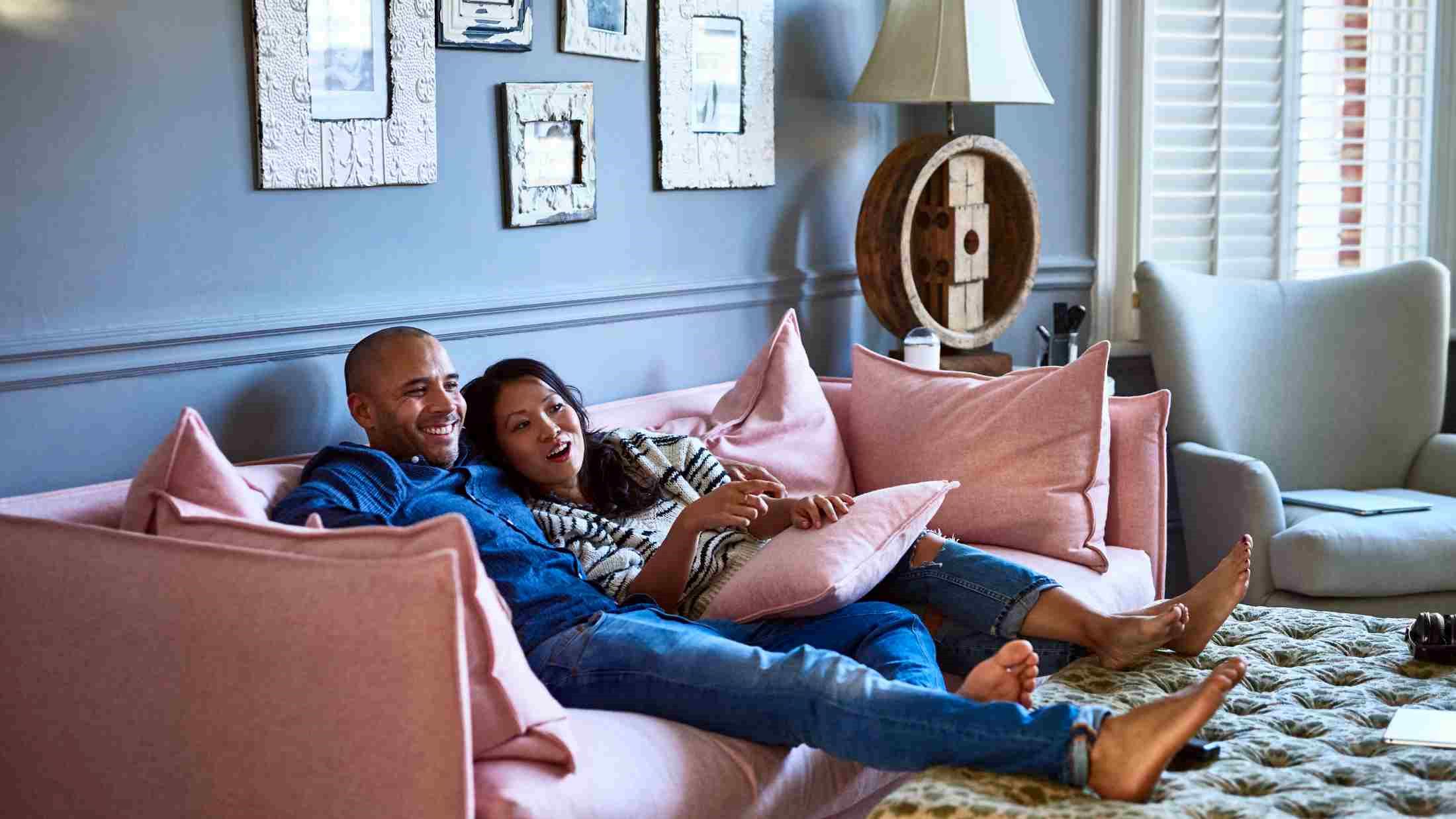 Couple at home watching television together on sofa