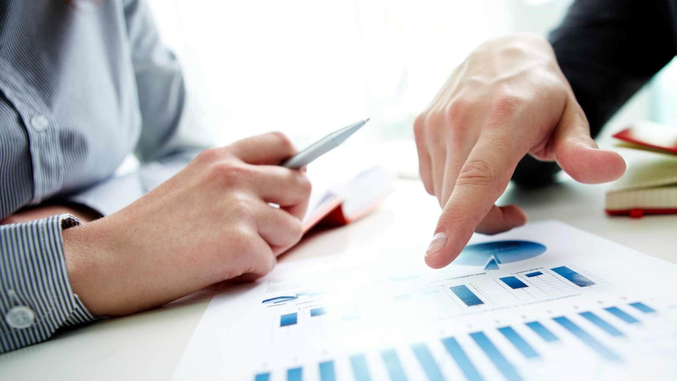 people pointing and looking at graphs on a piece of paper