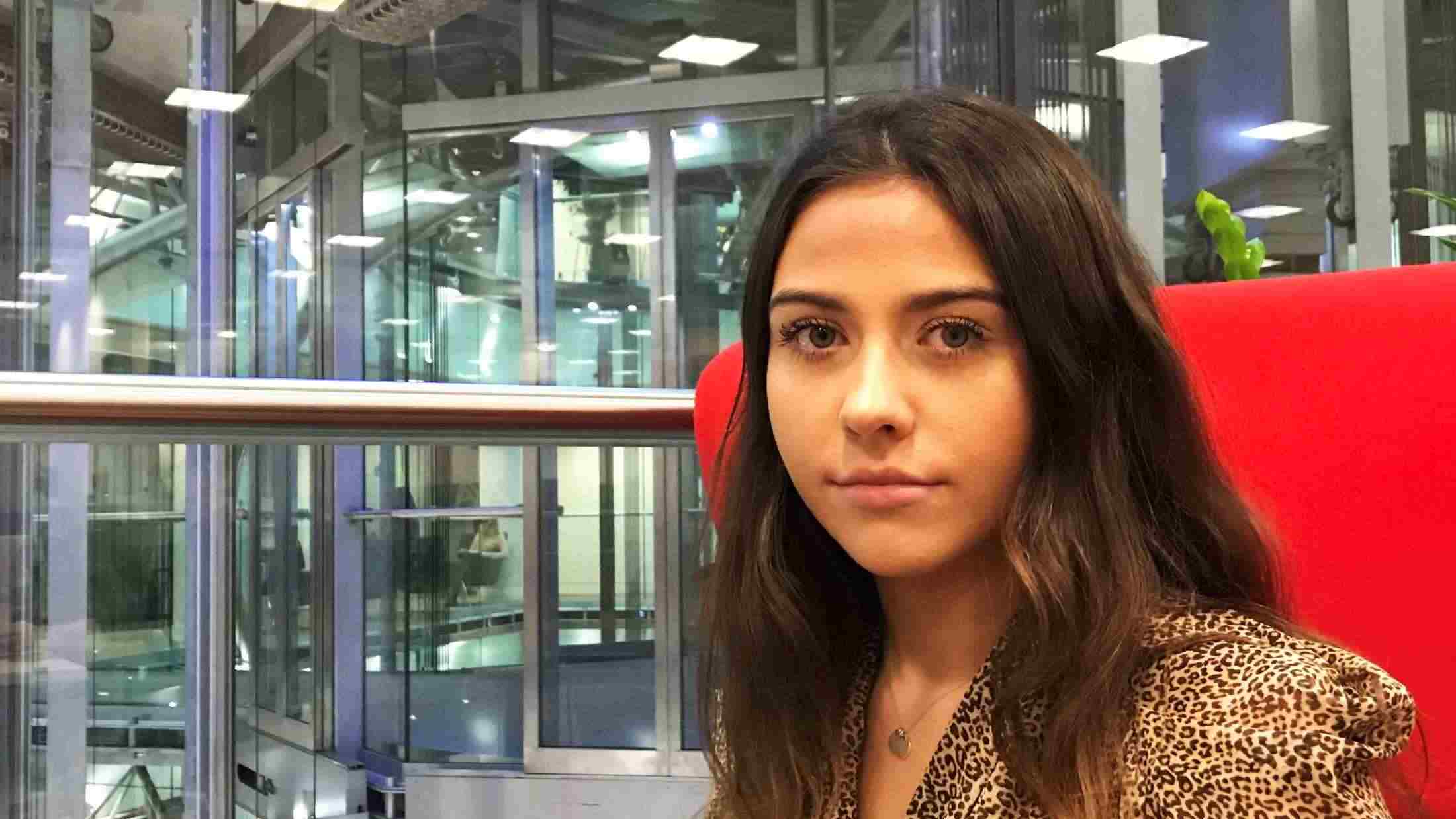 Mia Simpson, PR Apprentice, sat at in a red chair in AXA's London Office on Old Broad Street