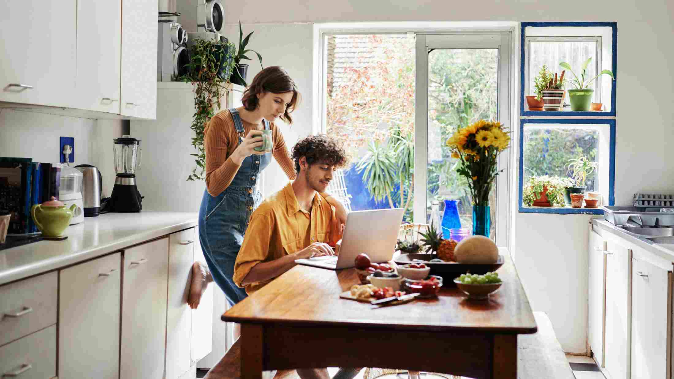 Loving couple drinking coffee in front of a computer at home