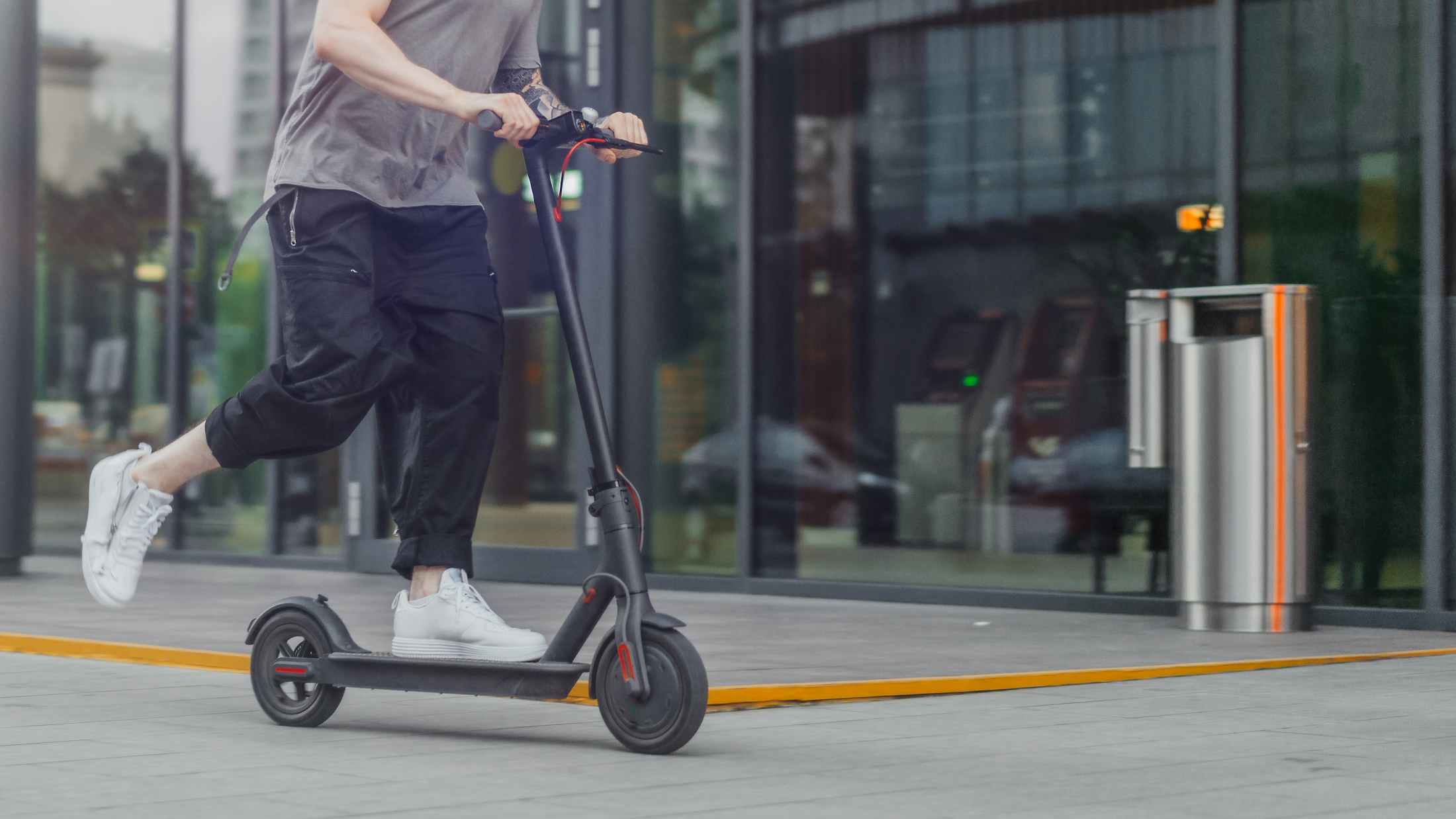 Man riding an electric scooter in front of an office building in the City