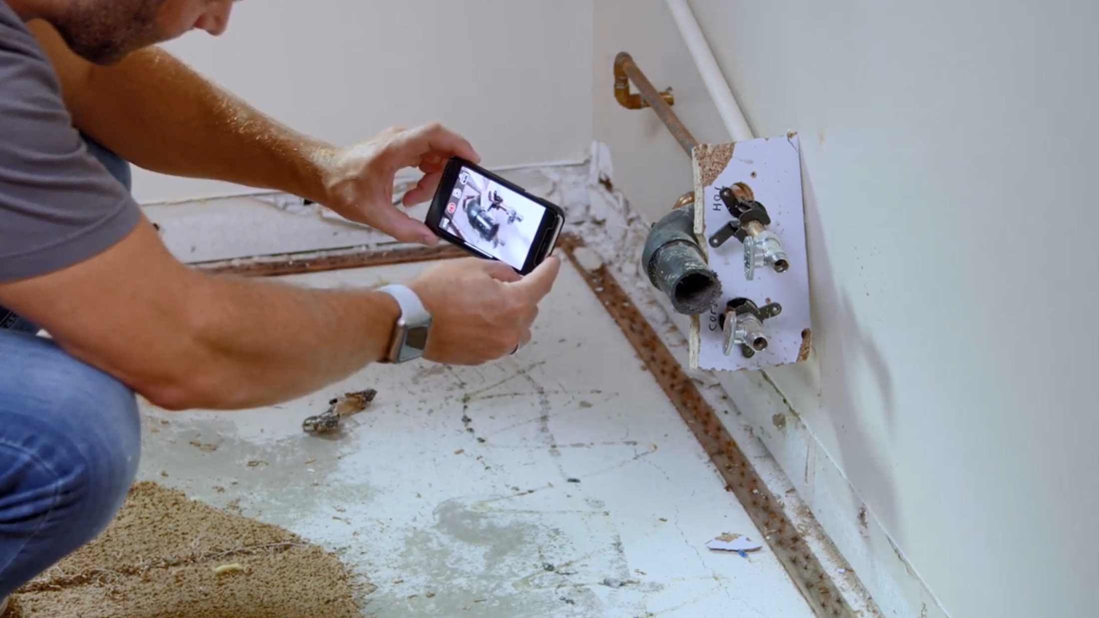 Man taking photo of pipework using ClaimXperience app on his phone