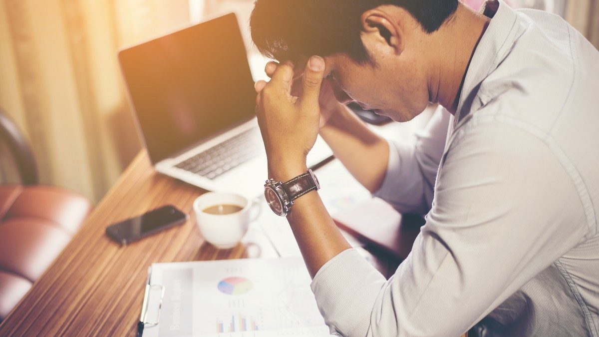 Man with heads in hands as he looks through his business accounts