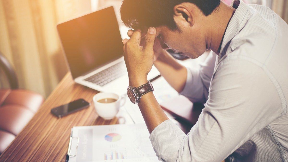 Man with heads in hands as he looks through his business accounts