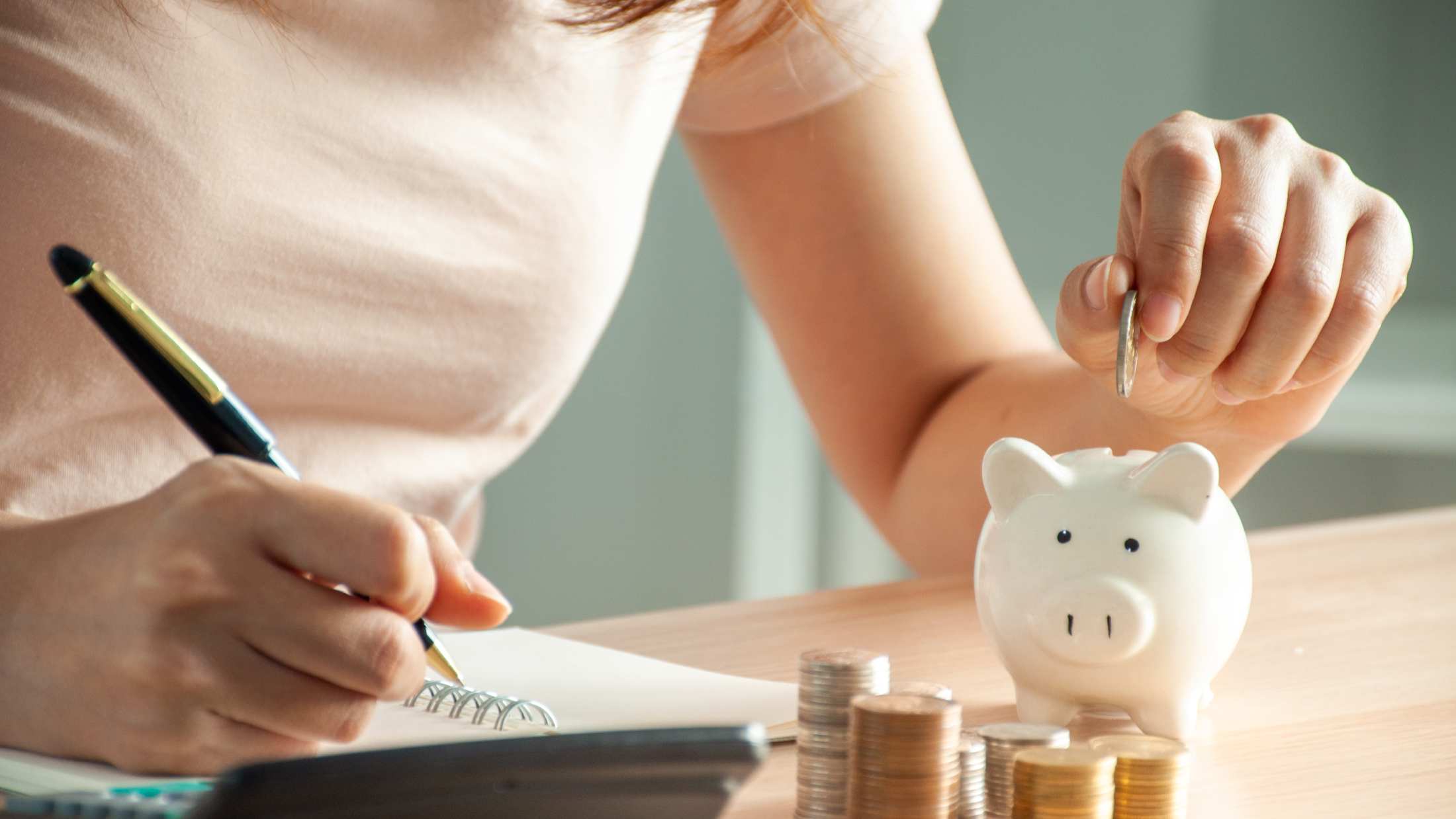 Midsection of woman putting coin in piggy bank