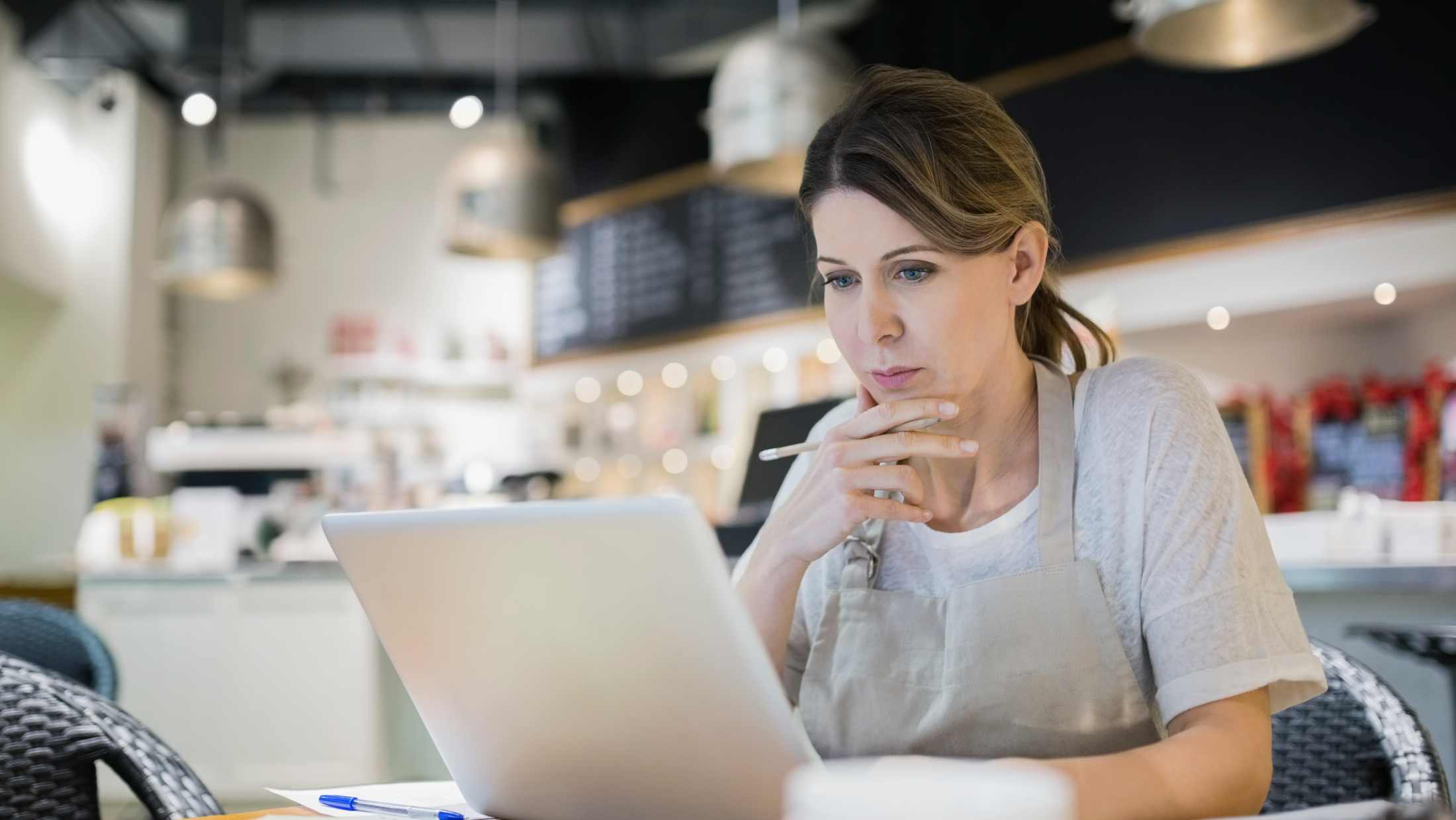 Serious business owner working at laptop in cafe