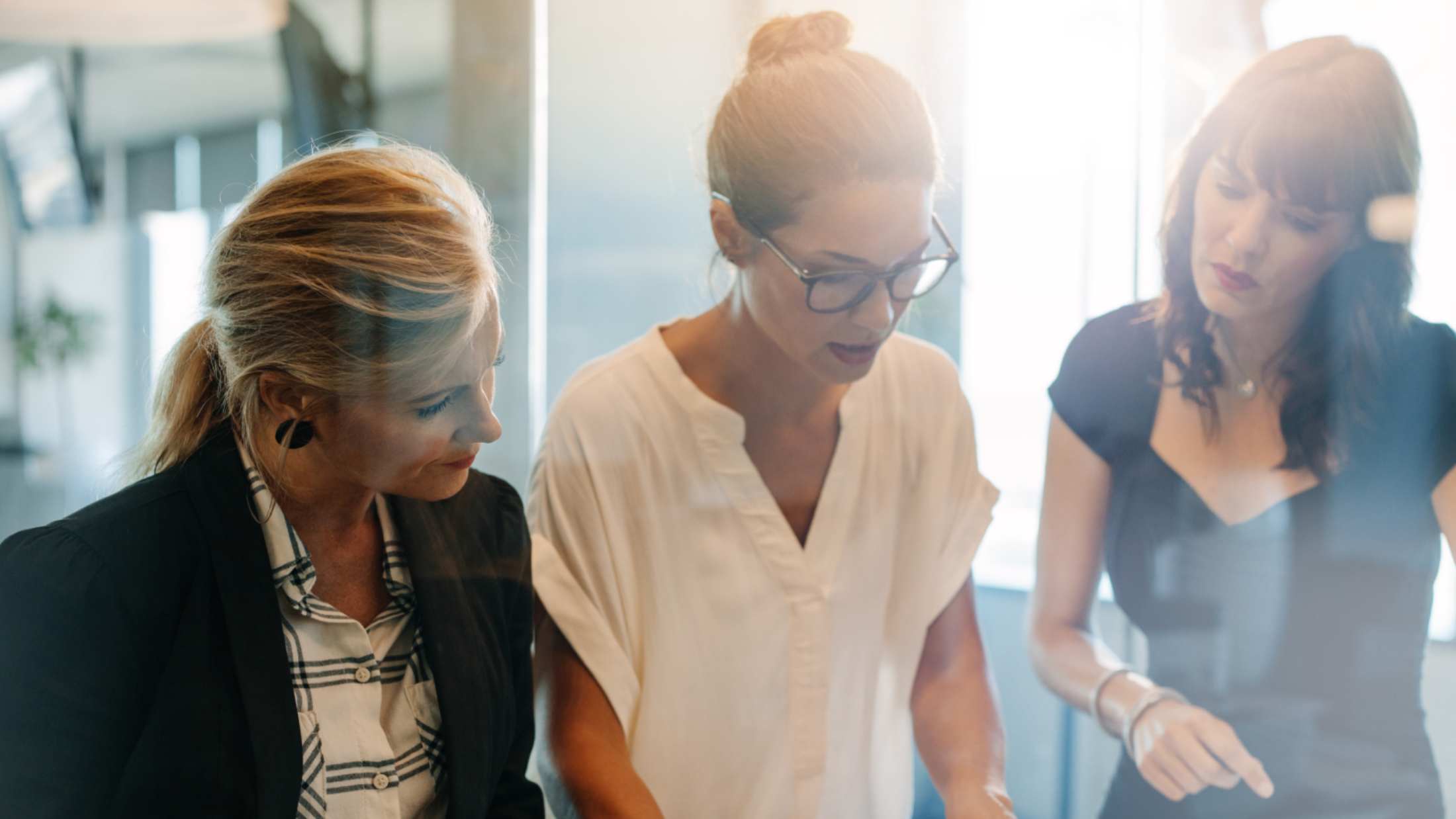 Three business women looking down at plans on a table