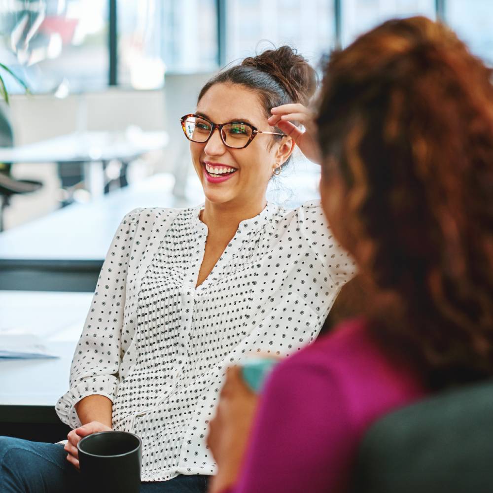 Woman holding a cup and laughing with her colleague