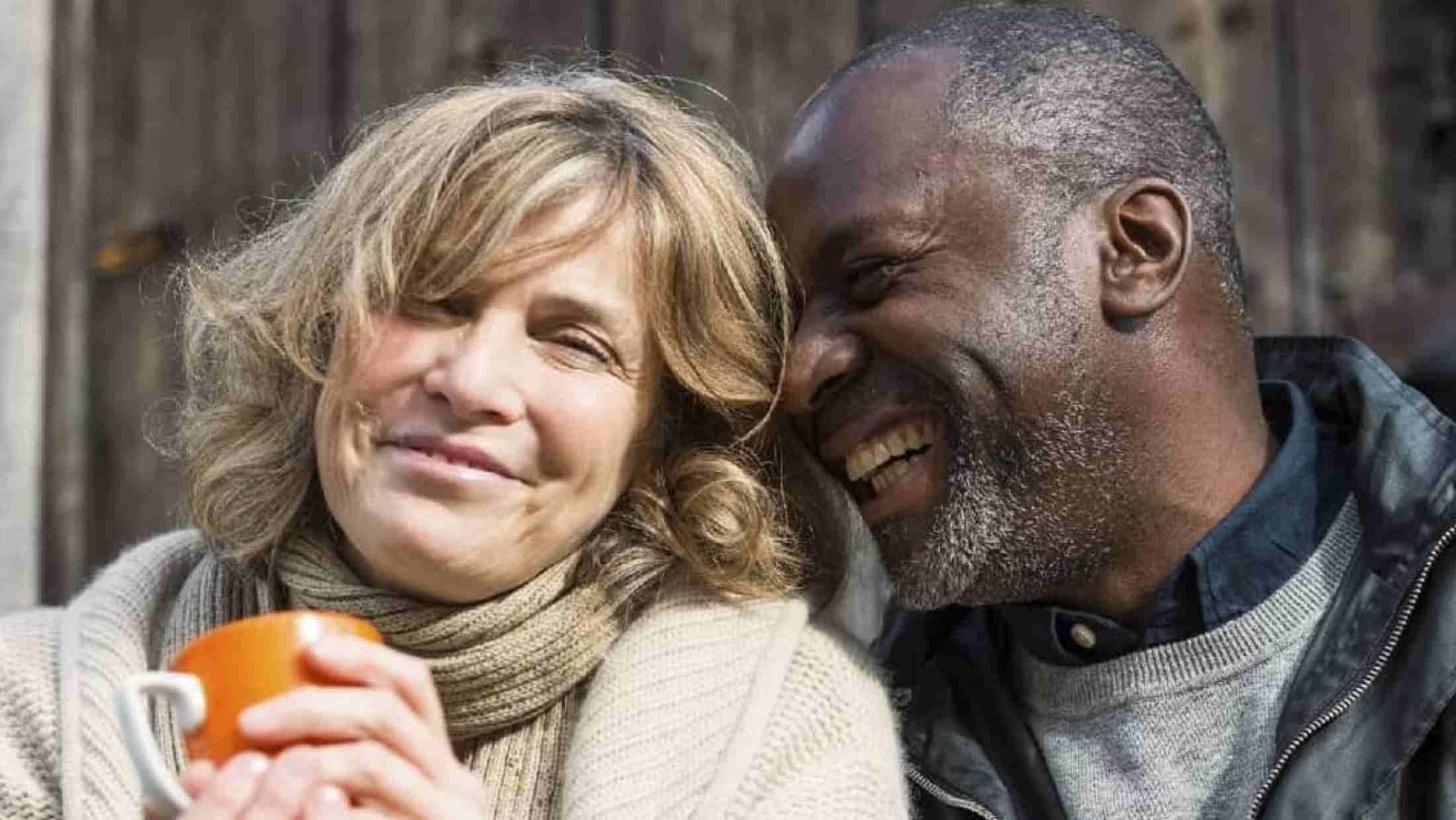 a male and a female couple smiling in front of their home