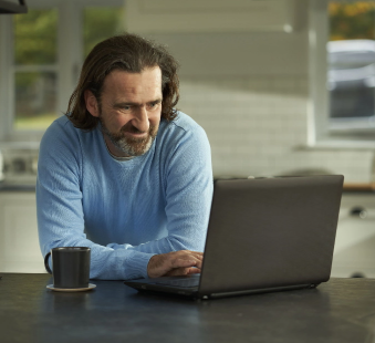 man with a coffee working on his laptop computer